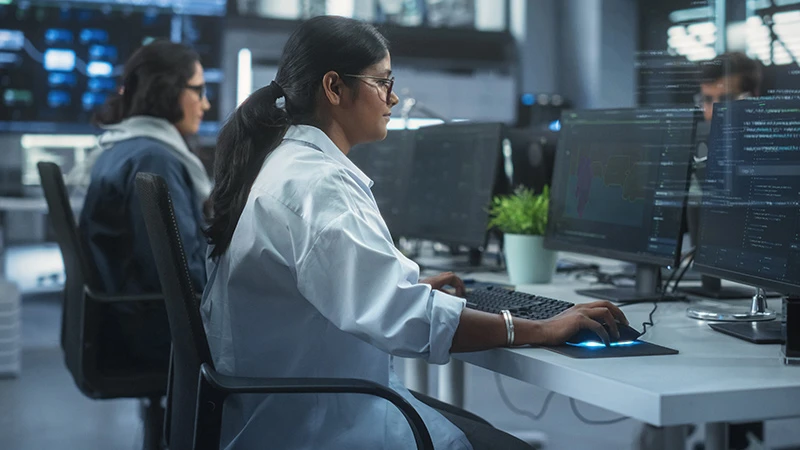 Two women sit in front of computer monitors doing annotation work.