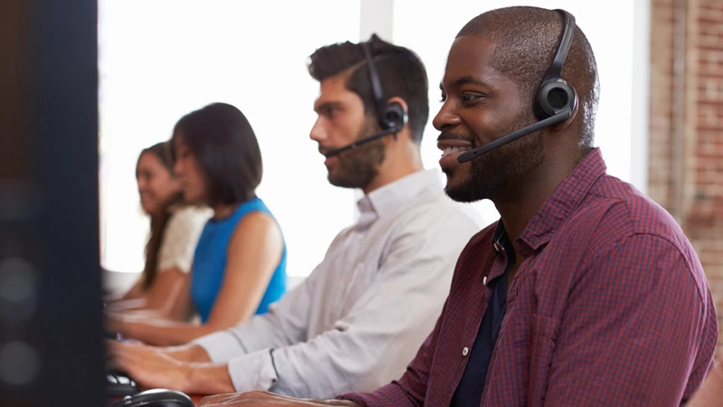 Four customer service agents with headsets looking at computer monitors