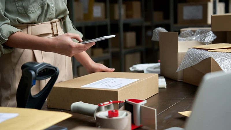 Photo of a person holding a smart phone to scan a package label, meant to represent an ecommerce seller