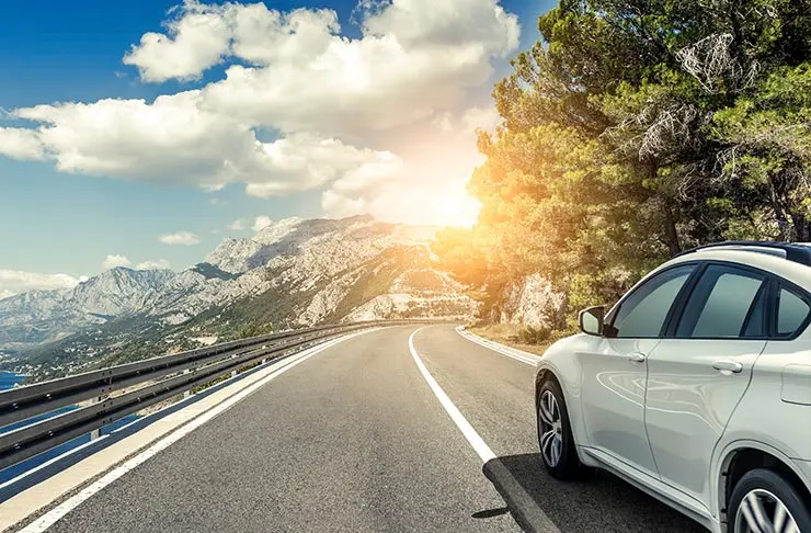 A car driving on a highway with mountains in the distance.