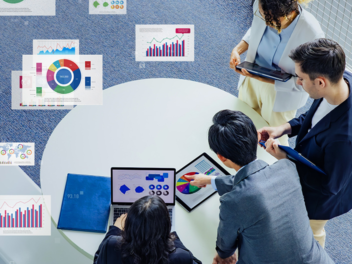 A group of professionals gathered around a table looking at analytical charts and graphs.