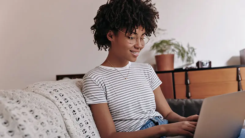 Woman sitting on a couch working on a laptop. 