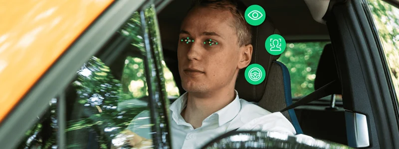 Person driving car with annotations meant to convey eye movement tracking or blink monitoring
