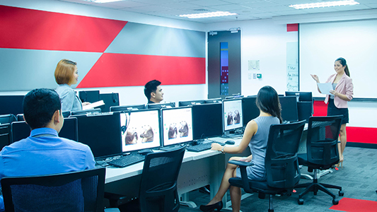 A woman presenting to a few workers at their work desks