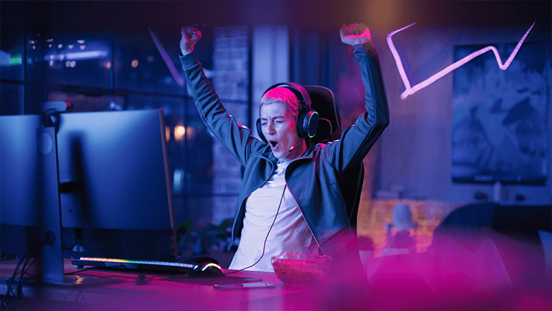 Person celebrating with their arms raised while sitting in front of a computer for gaming