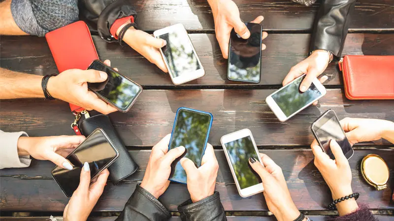 Group of people with their mobile phones out around a table 
