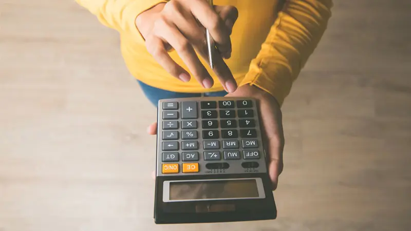 woman determining cost on calculator 