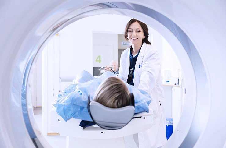 A medical professional placing someone inside a medical imaging machine.