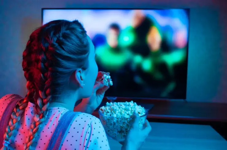 A woman enjoying her popcorn while she is watching a movie