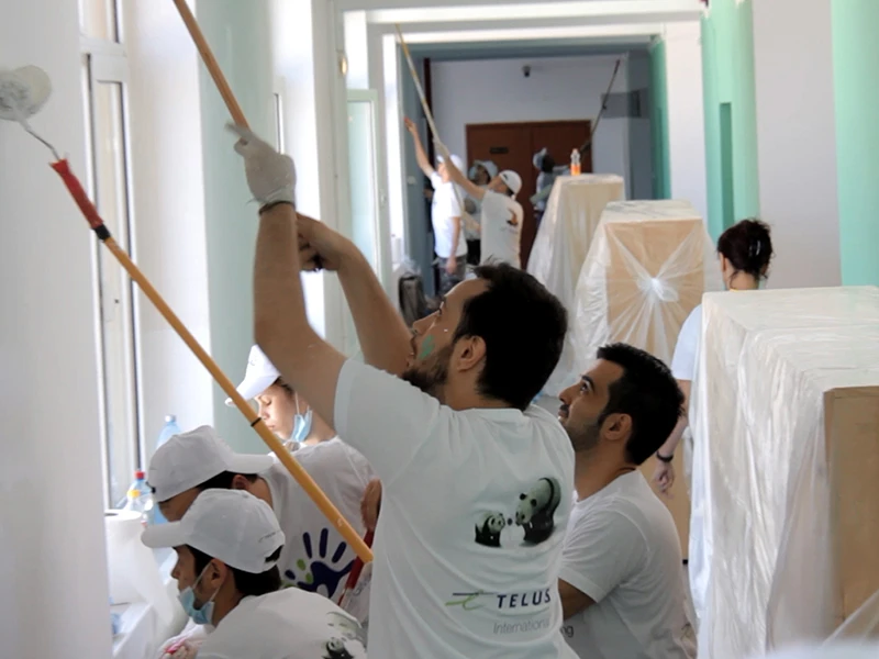 Team members demonstrating corporate social responsibility by painting walls in a children's center