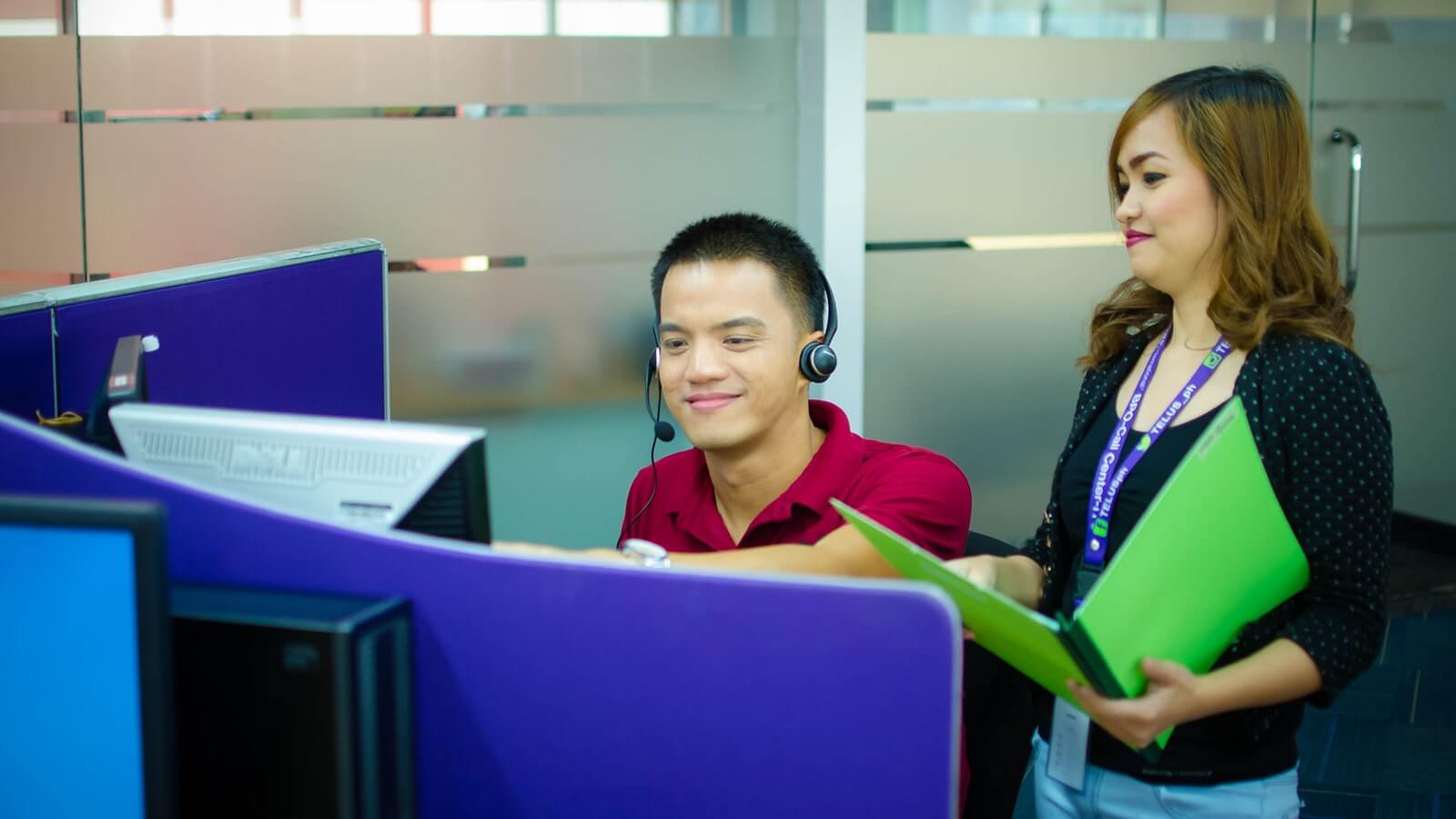 A call center employee showing something on his screen to his boss