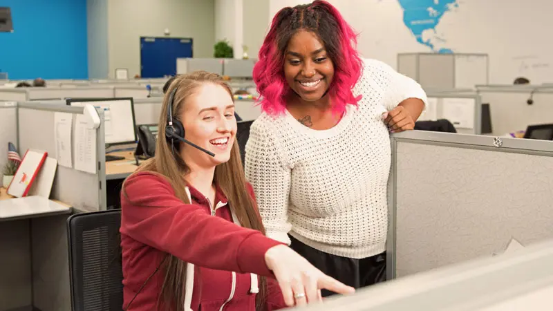 Two female TELUS International team members in the call center
