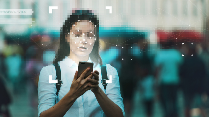Person using smart phone; effects applied to her face to represent facial recognition