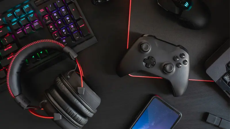 gamers work space with controller, keyboard, headphones, mouse and smartphone