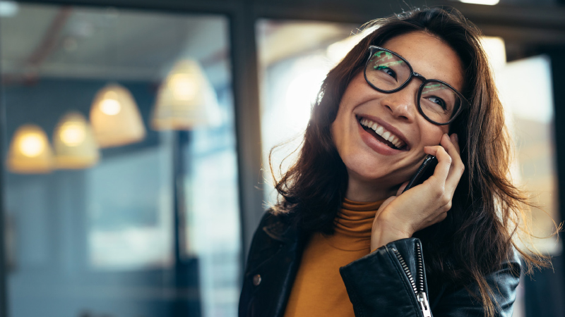 A smiling woman speaking on a cellphone.