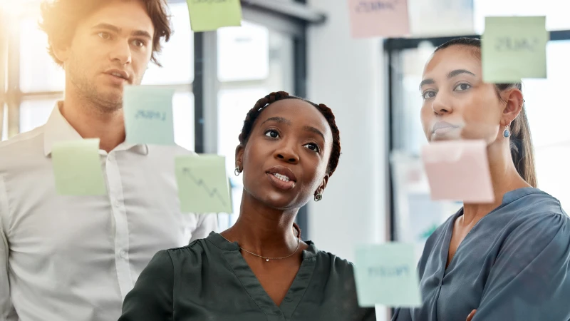 Photo of three colleagues establishing priorities with sticky notes