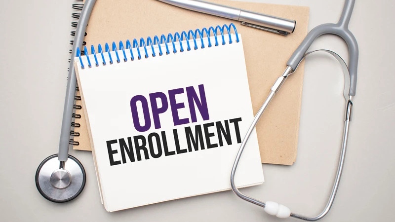 Coiled notepad with text that reads "Open Enrollment" accompanied by various medical devices
