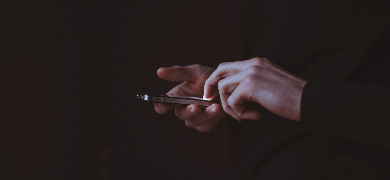 Hands using a smartphone on a black background