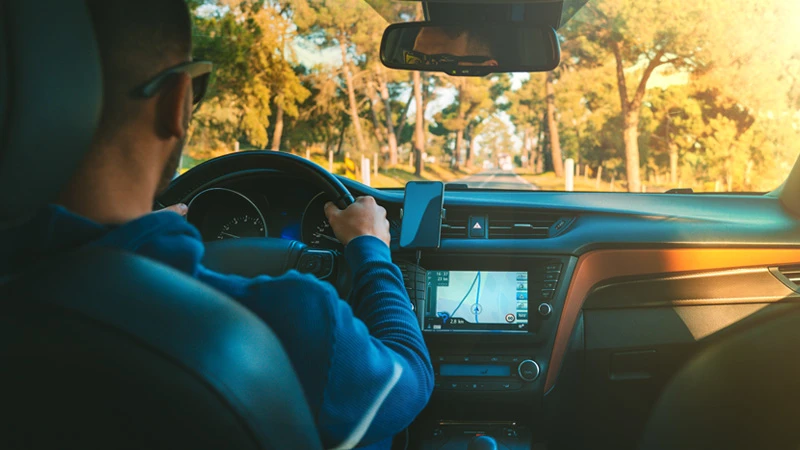 Photo of a person driving a car with the car's GPS system in view