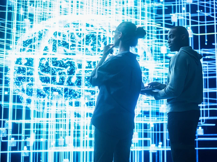 A man and a woman standing in front of a large digital representation of a brain.