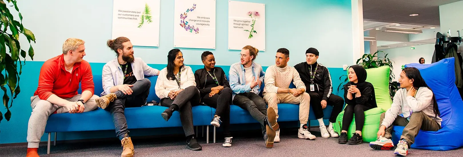 TELUS International employees sitting on a couch socializing at the Tampere office. 