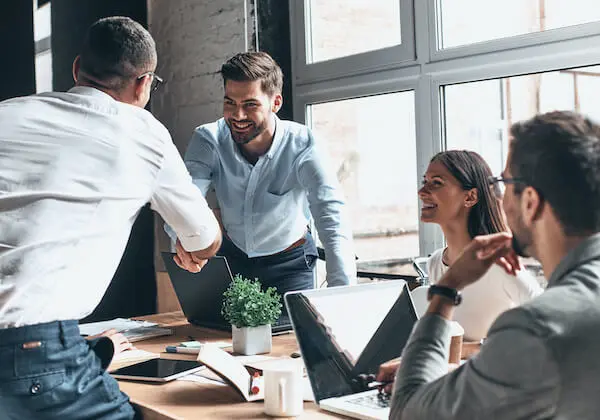 Two co-workers shaking hands over a meeting