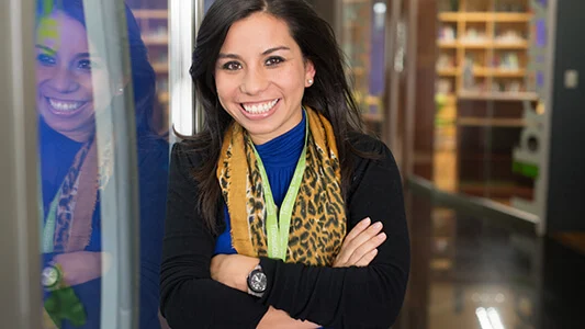 A woman with arms crossed and a leopard print scarf smiling