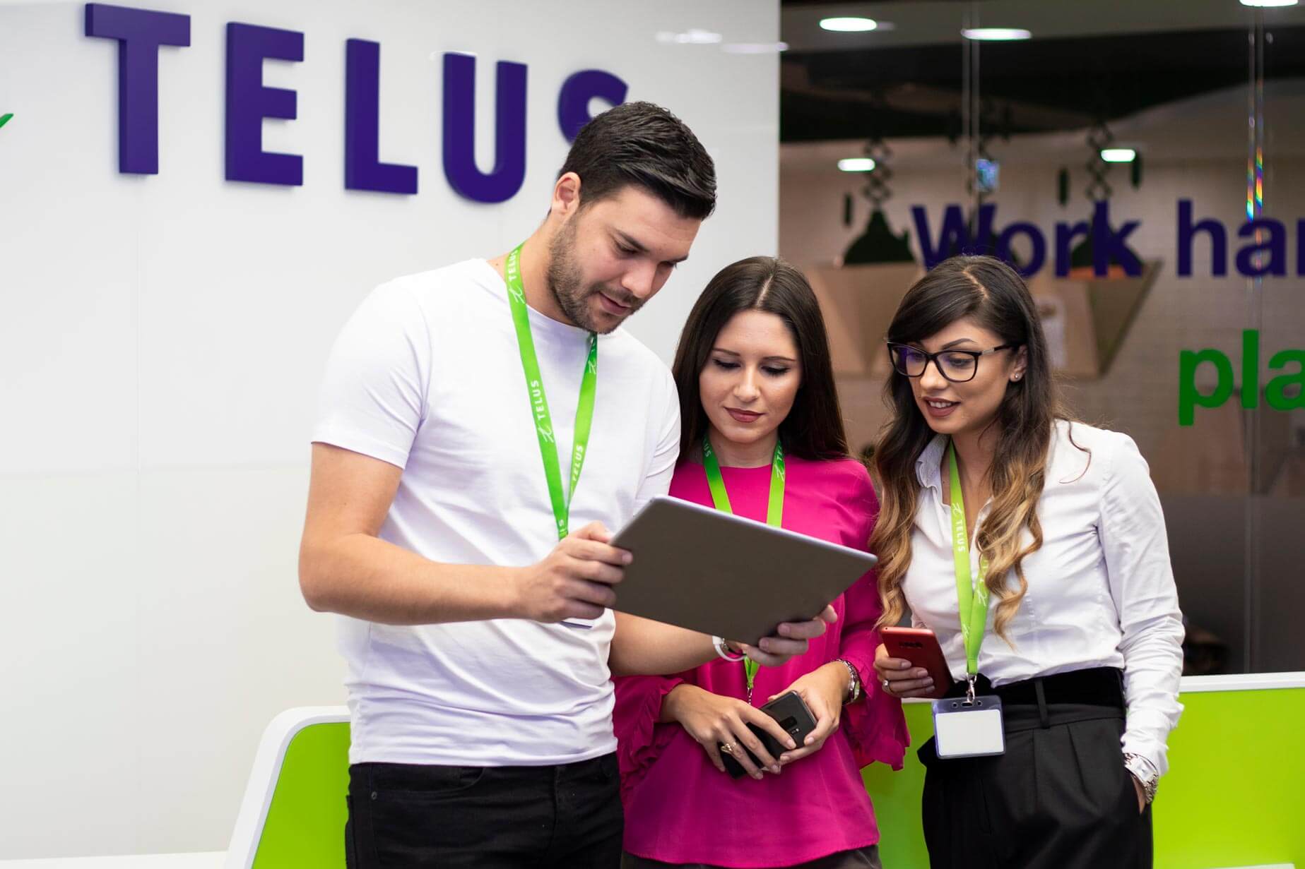 Three colleagues gathered around an iPad.