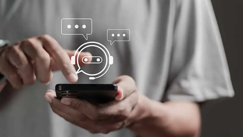 Man using his mobile device with a chatbot illustration above the device.
