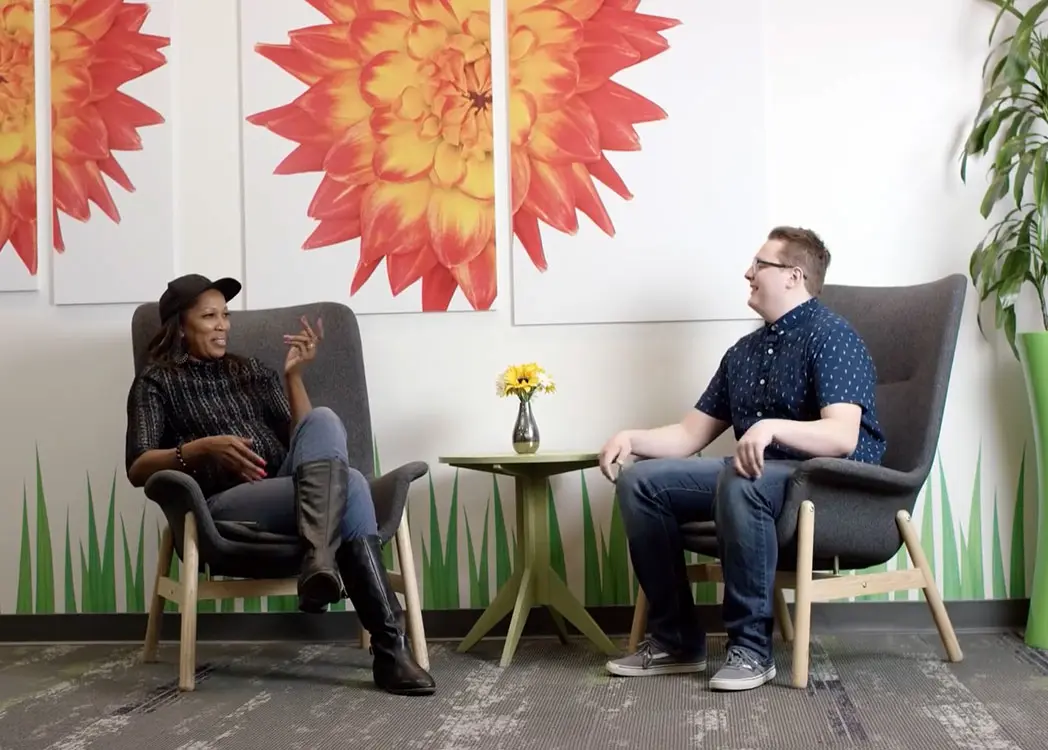 Two colleagues seated and having a discussion in front of artwork.