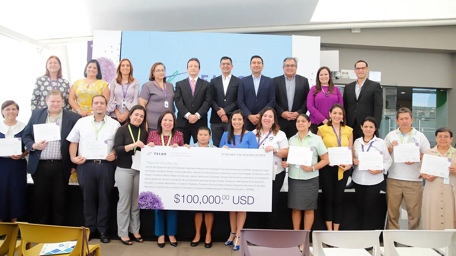 A group of people smiling and holding a large $100,000 USD cheque.