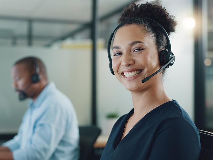 Photograph of a customer service agent wearing a headset and smiling