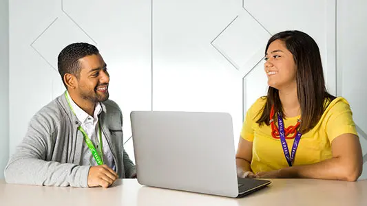 two workers having a conversation around a laptop