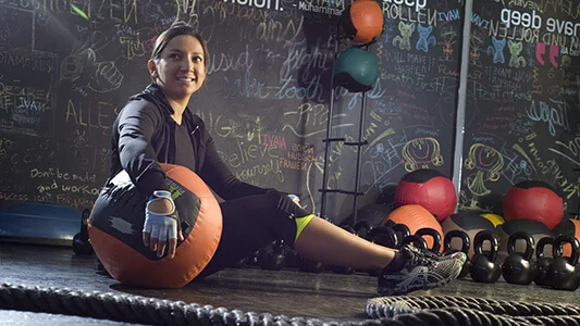 A woman at the gym holding a weighted ball