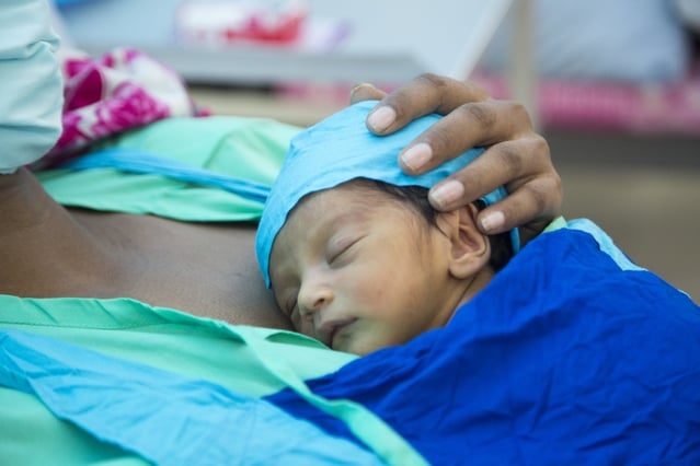 Newborn baby lying on mother's chest, symbolizing maternal and newborn care.