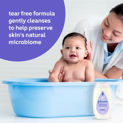 Mother bathing baby in a blue tub with a Johnson's Baby product bottle beside them. Text reads: "tear free formula gently cleanses to help preserve skin's natural microbiome"