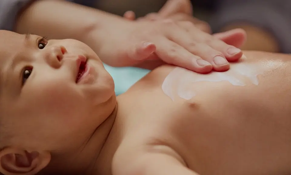 Article card Guide to Newborn Skin Care, Image of a woman gently massaging her baby's chest
