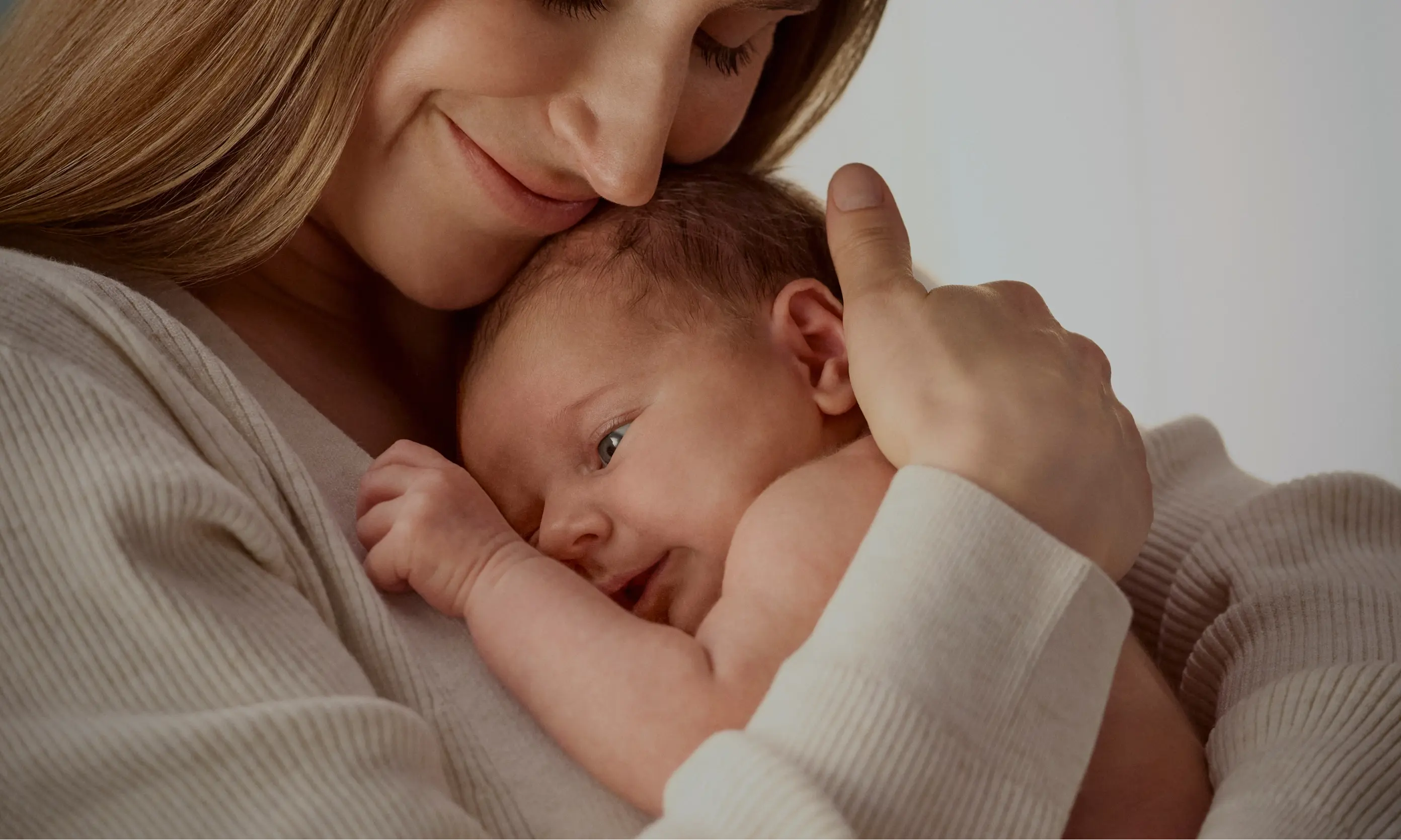 Mother and her baby hug, showing a moment of affection and tenderness.