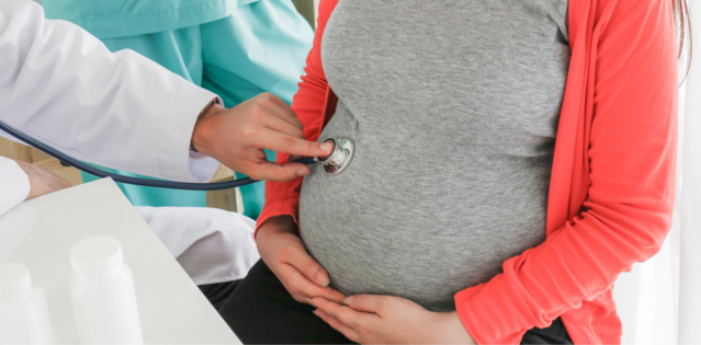 Doctor using a stethoscope on a pregnant woman's belly, highlighting the importance of maternal healthcare