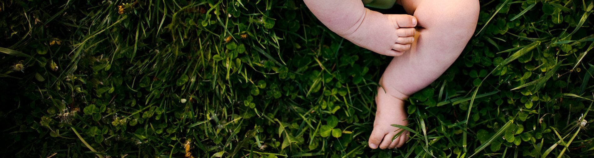 Close-up of a baby's feet resting on green grass, emphasizing gentle and natural elements.