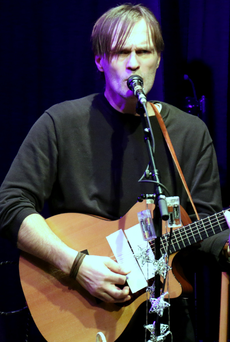 Christoph Raffetseder singend mit Gitarre auf einer Bühne.