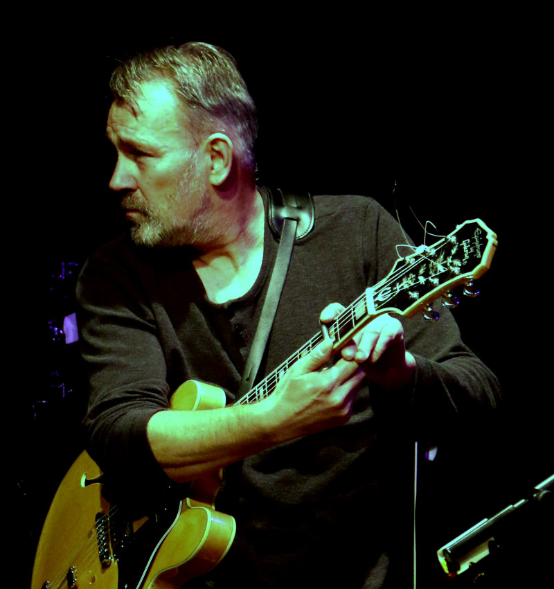 Andreas Raffetseder mit einer Gitarre in der Hand auf der Bühne.