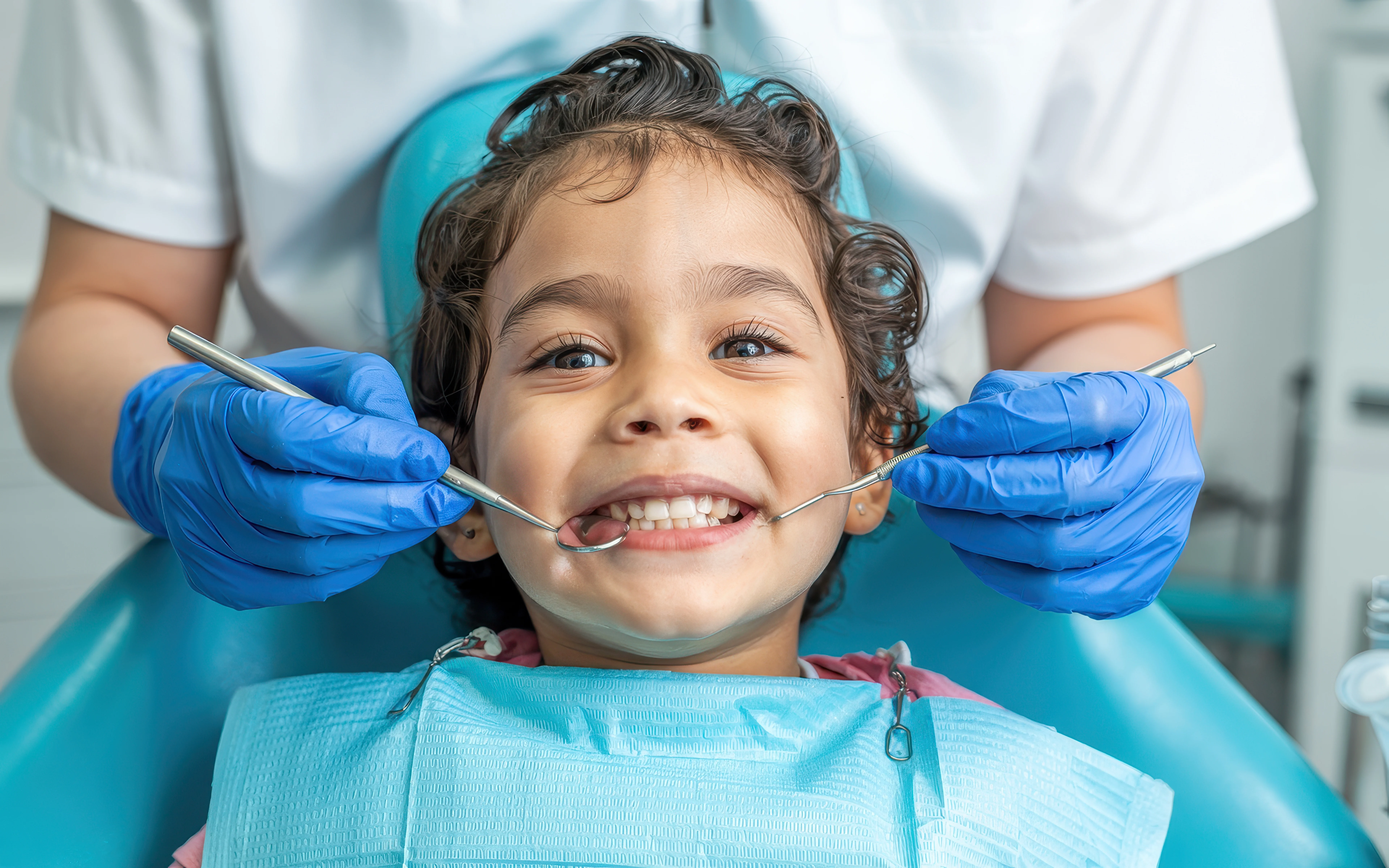 Hijyenist ile diş muayenesinde gülümseyen çocuk 