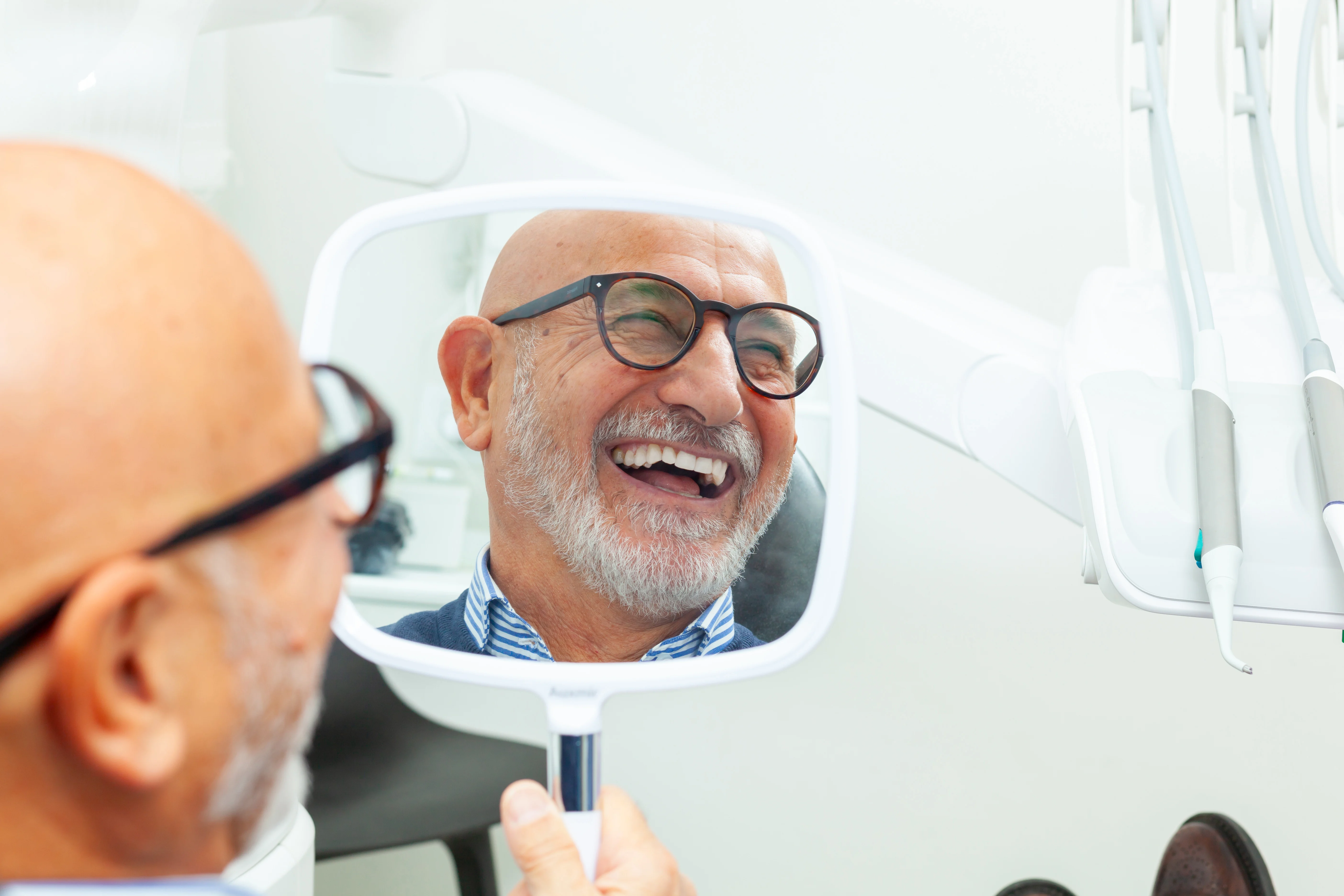 Yaşlı erkek hastanın diş aynasındaki gülümseyen yansıması. 