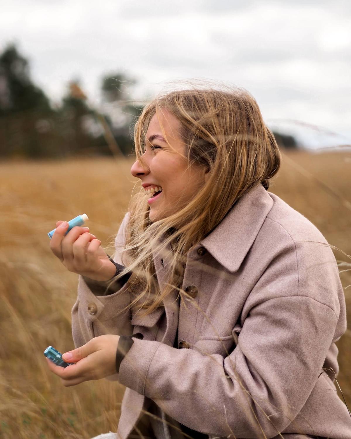 Curated image of a female social media influencer holding a Blistex lip balm. 