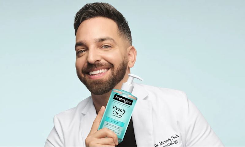 Doctor Muneeb Shah, Dermatologist, holding a bottle of Evenly Clear™ Acne Cleanser