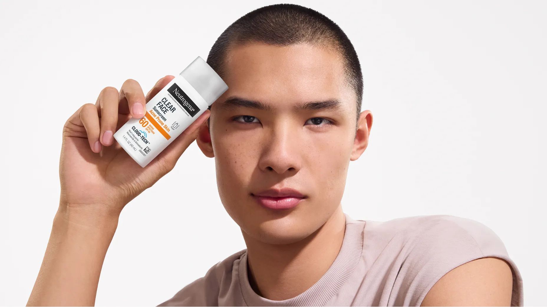 A Man with clear skin holding a bottle of Neutrogena® Cloud Tech™ Clear Face Sunscreen for Acne Prone Skin