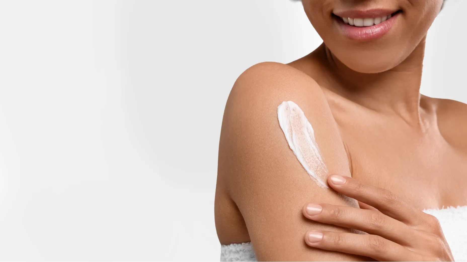 Woman smiling while applying Neutrogena® Sunscreen to arm