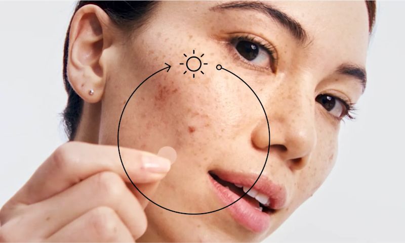 A young woman with an Neutrogena® mini acne patch on her cheek.