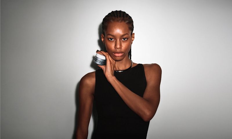 Woman with healthy skin holding up a jar of Neutrogena® Rapid Wrinkle Repair® Retinol Regenerating Cream Fragrance Free